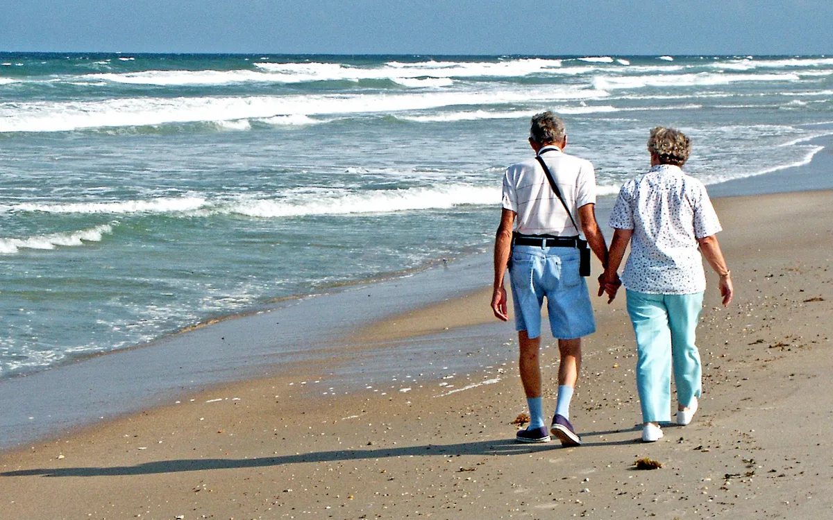 A retired couple walking along the beach